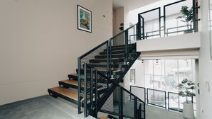 A staircase with black railings and wooden steps, leading to a balcony with a view of the outside. - Studio365 Apartment (Chiang Mai)