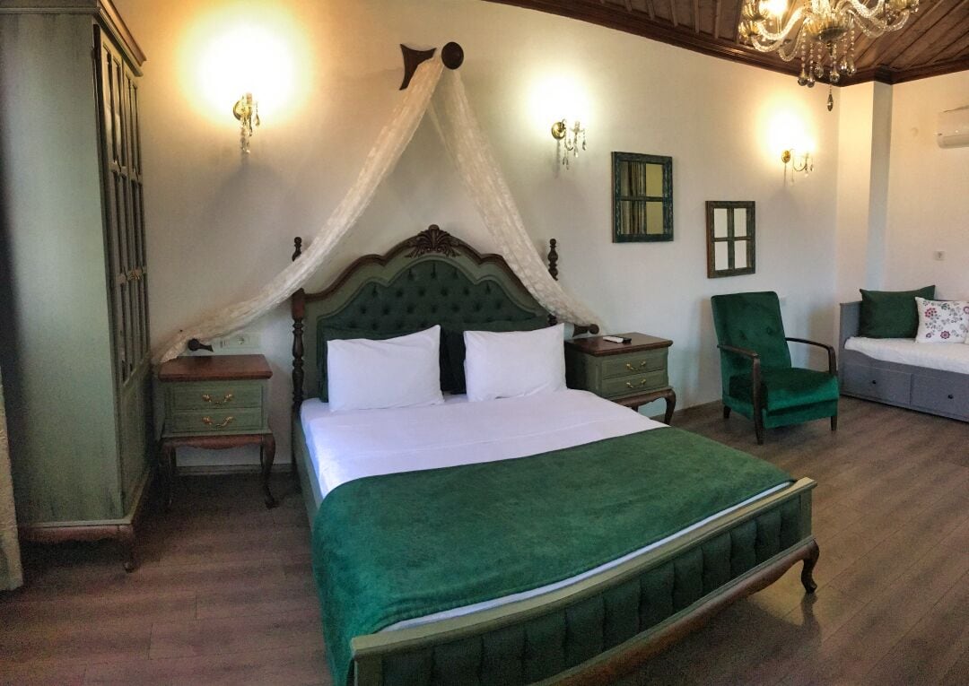 Un dormitorio con cama con dosel, una mesita de noche, una silla y un aparador.