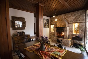 A cozy room with a stone fireplace, wooden beams, and a dining table with a placemat.