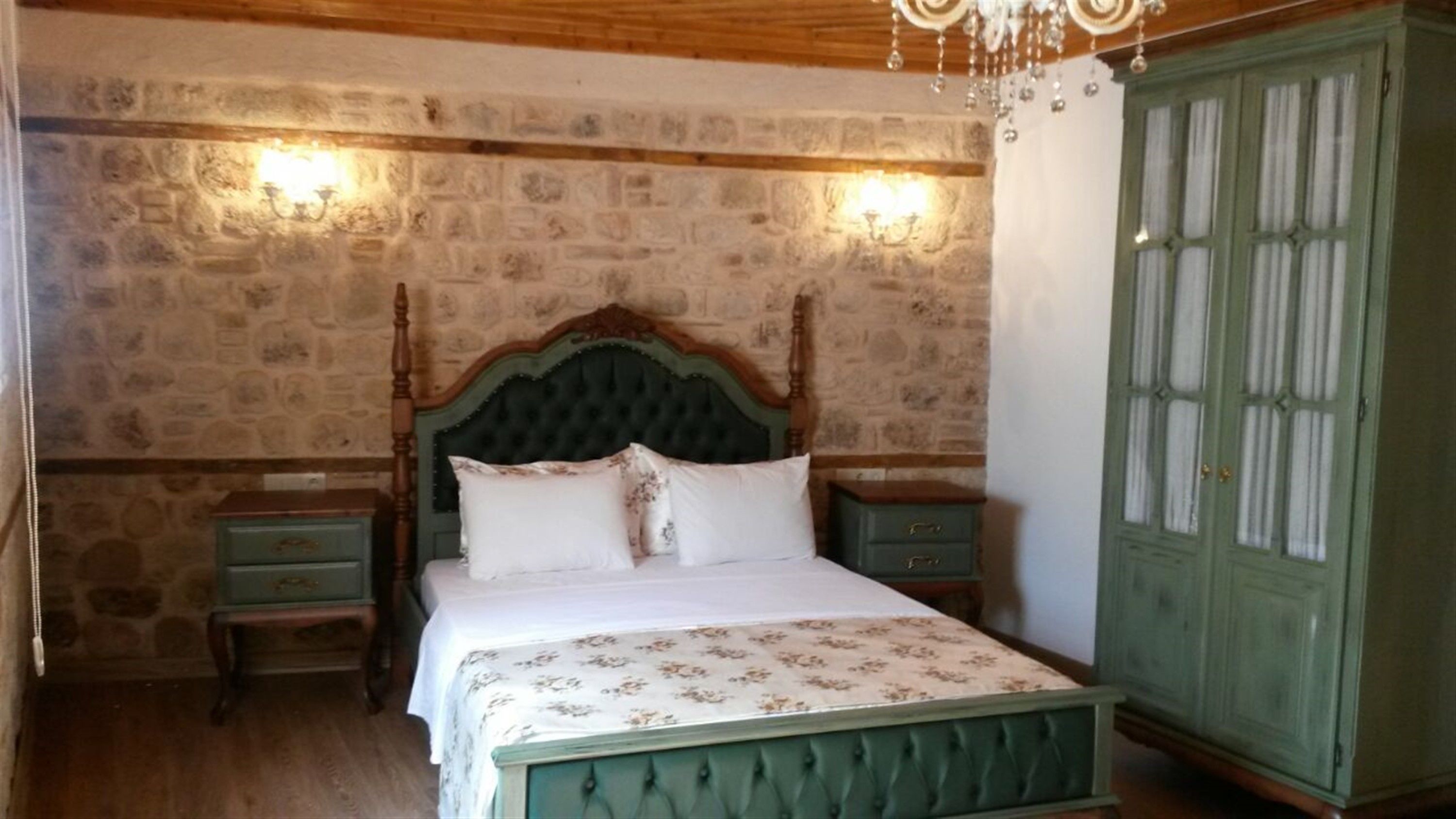 Un dormitorio con cama con dosel, un armario verde y paredes con diseño de piedra.