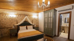 A bedroom with a four-poster bed, a wooden ceiling, a green wardrobe, and a wooden floor.