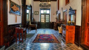 A hallway with a patterned floor, wooden furniture, a chandelier, and a door with glass panels.