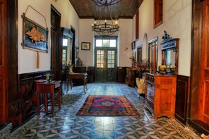 A hallway with a patterned floor, wooden furniture, a chandelier, and a door with glass panels.