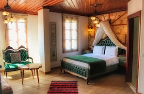 Ein traditionell eingerichtetes Schlafzimmer mit einem Himmelbett, einem grünen Sessel und einem Holztisch.