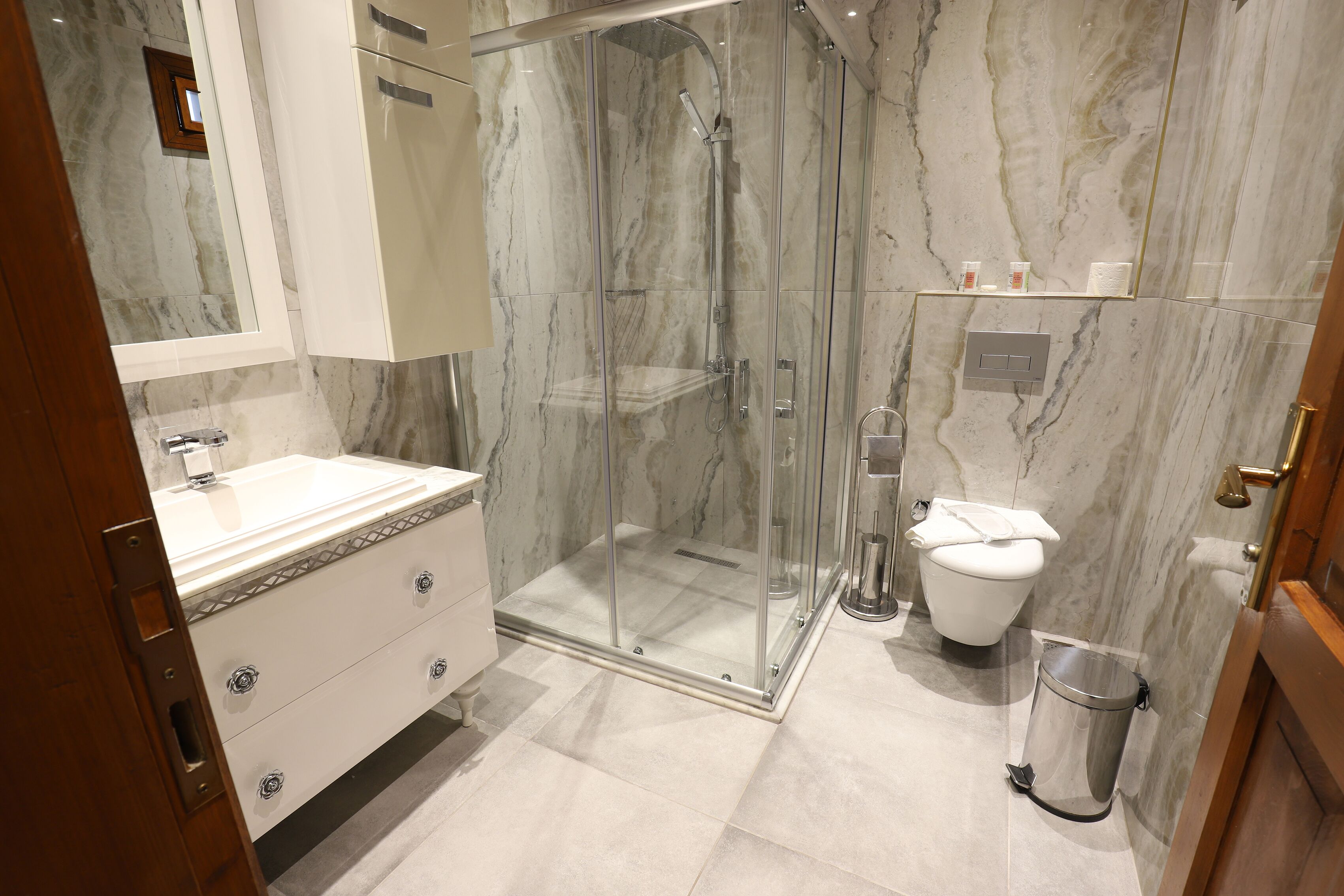 Un baño moderno con ducha de vidrio, un lavamanos blanco y un inodoro.