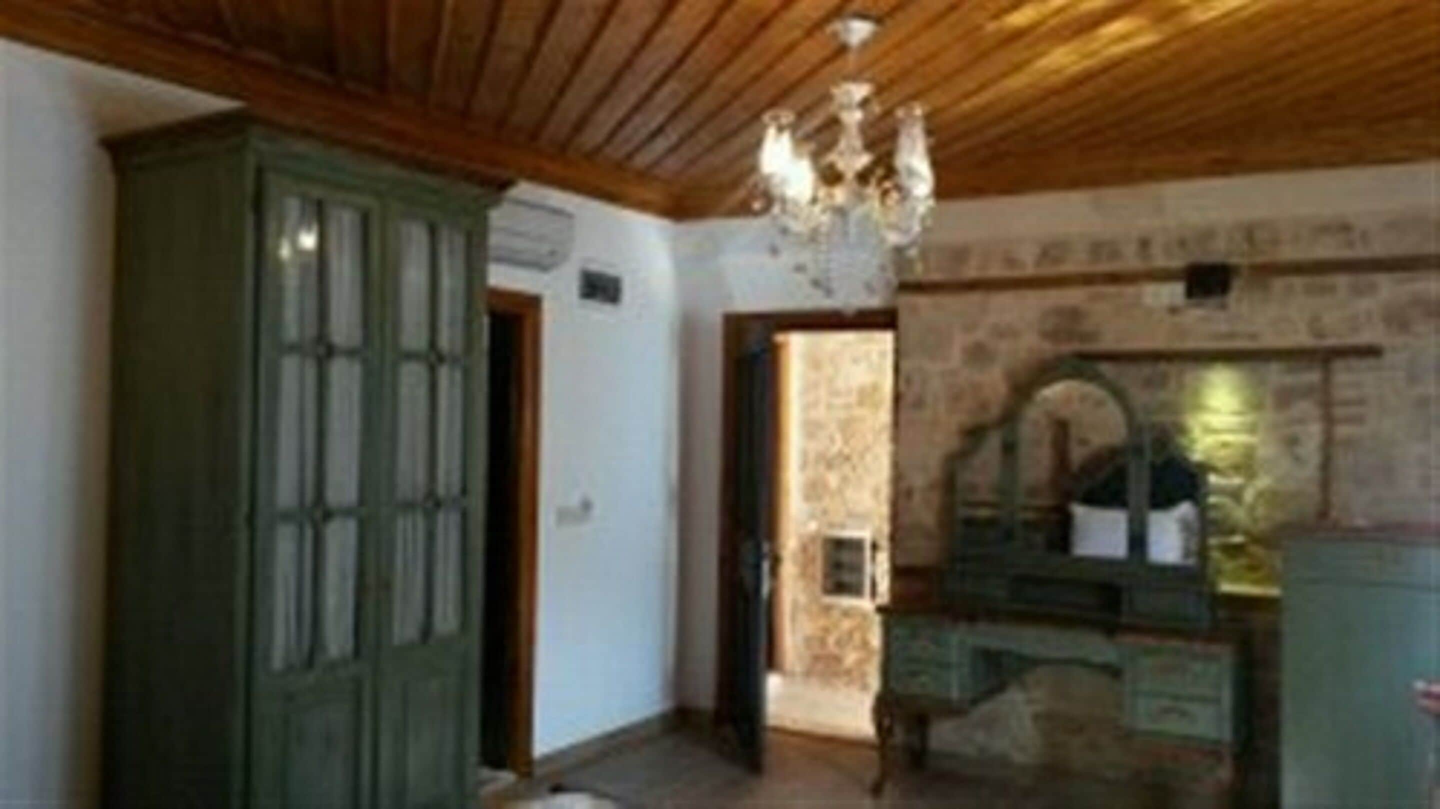 Una habitación con techo de madera, un aparador verde y una pared de piedra.