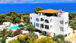 A modern building with a rooftop terrace, a swimming pool, and a view of the sea.
