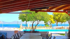 An outdoor dining area with a view of a pool and the sea.