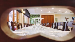 Un comedor con una mesa larga dispuesta para una comida, sillas y un centro de mesa decorativo.