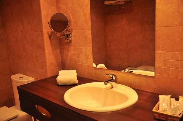 A bathroom with a round mirror, a sink, and a towel rack.