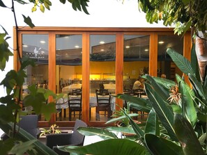 A restaurant with a glass enclosure, wooden frames, and indoor plants.