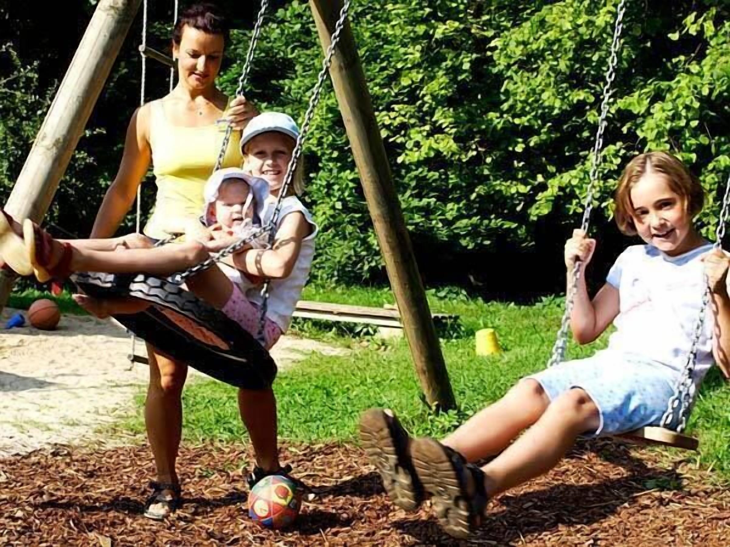 A playground with swings and a ball on the ground.