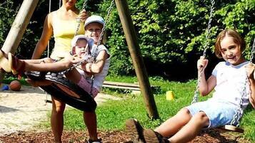 A playground with swings and a ball on the ground.