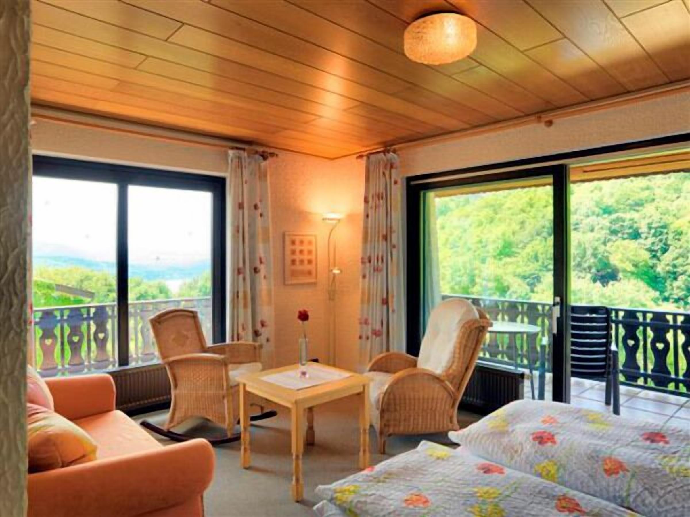 Una habitación con balcón, cama, mesa y dos sillas.