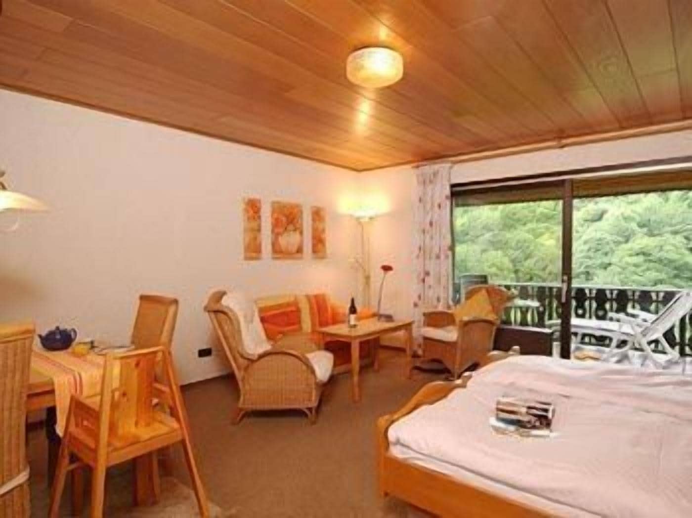 Una habitación acogedora con una cama, un escritorio y dos sillas. Hay tres cuadros en la pared y una ventana con vistas a zonas verdes.