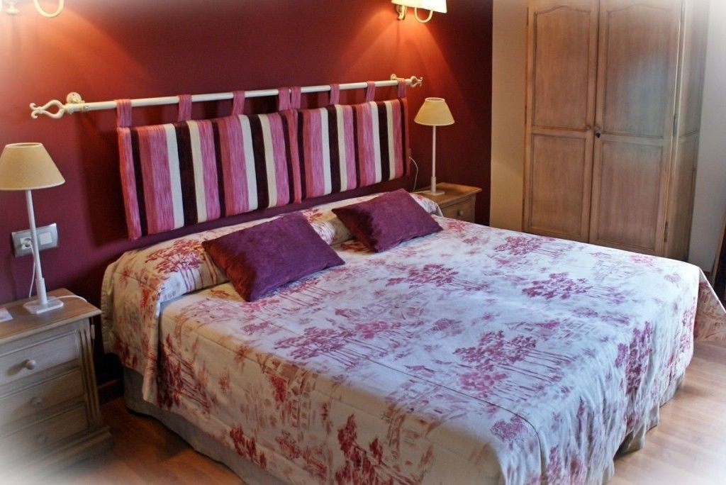 A bedroom with a bed, a nightstand, a lamp, and a wardrobe.