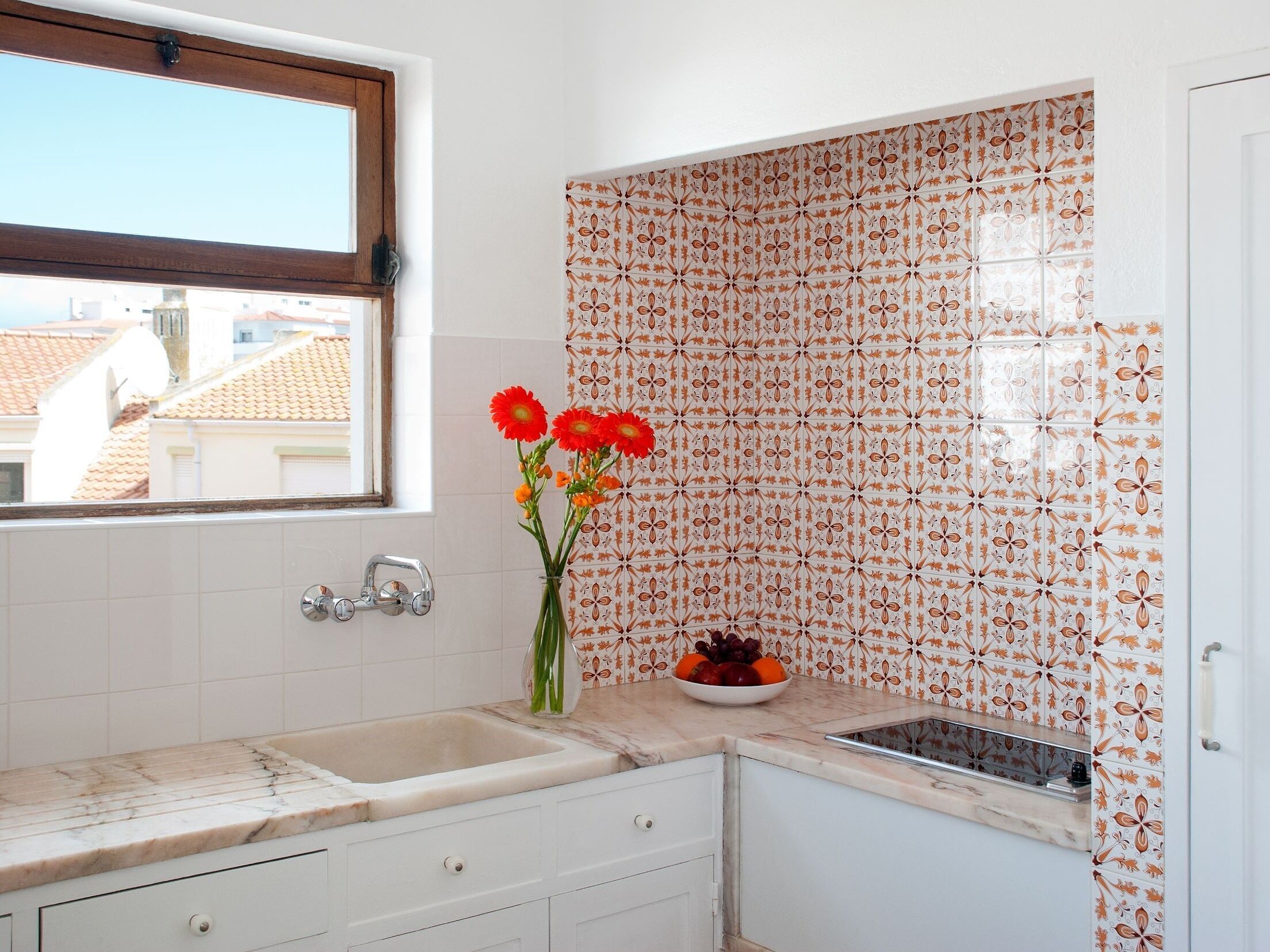 A kitchen with white cabinets, a marble countertop, a sink, and a window with a view of buildings.