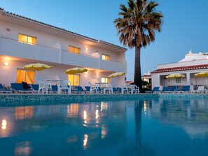 A hotel with a pool, lounge chairs, and umbrellas. - Apartamentos Turísticos Sollagos (Lagos)