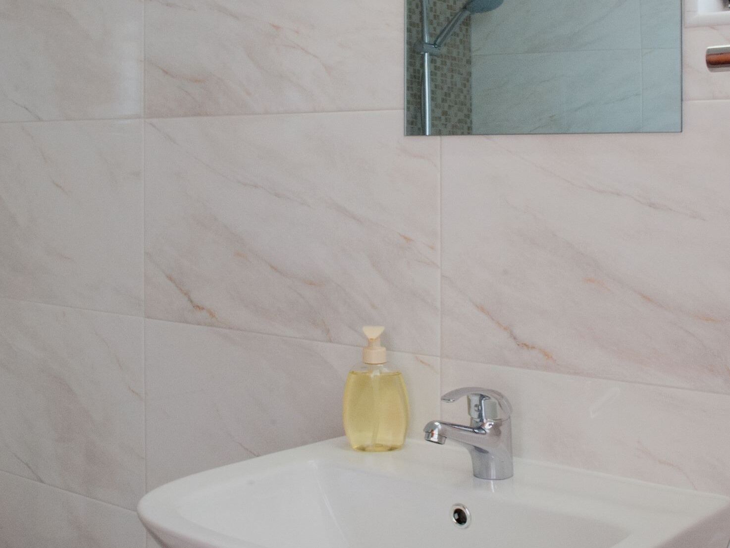 Une salle de bain avec un lavabo blanc, un robinet chromé et un distributeur de savon.