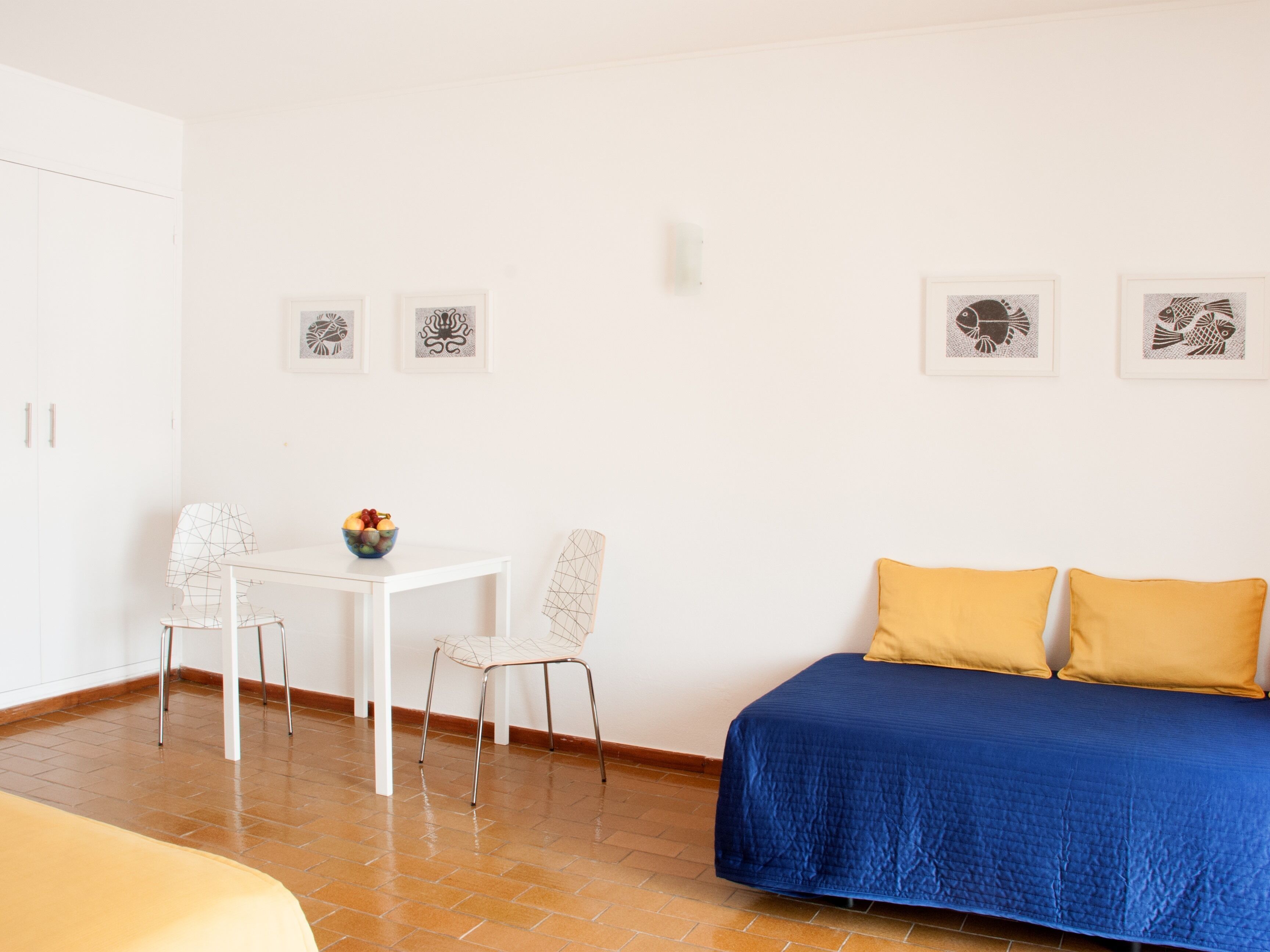 Ein Zimmer mit einem Bett, einem Tisch mit Stühlen und einer Obstschale.