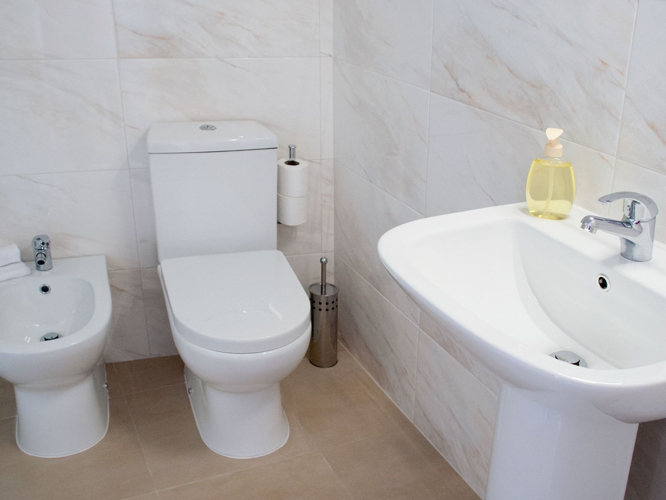 Een badkamer met toilet, bidet en wastafel.
