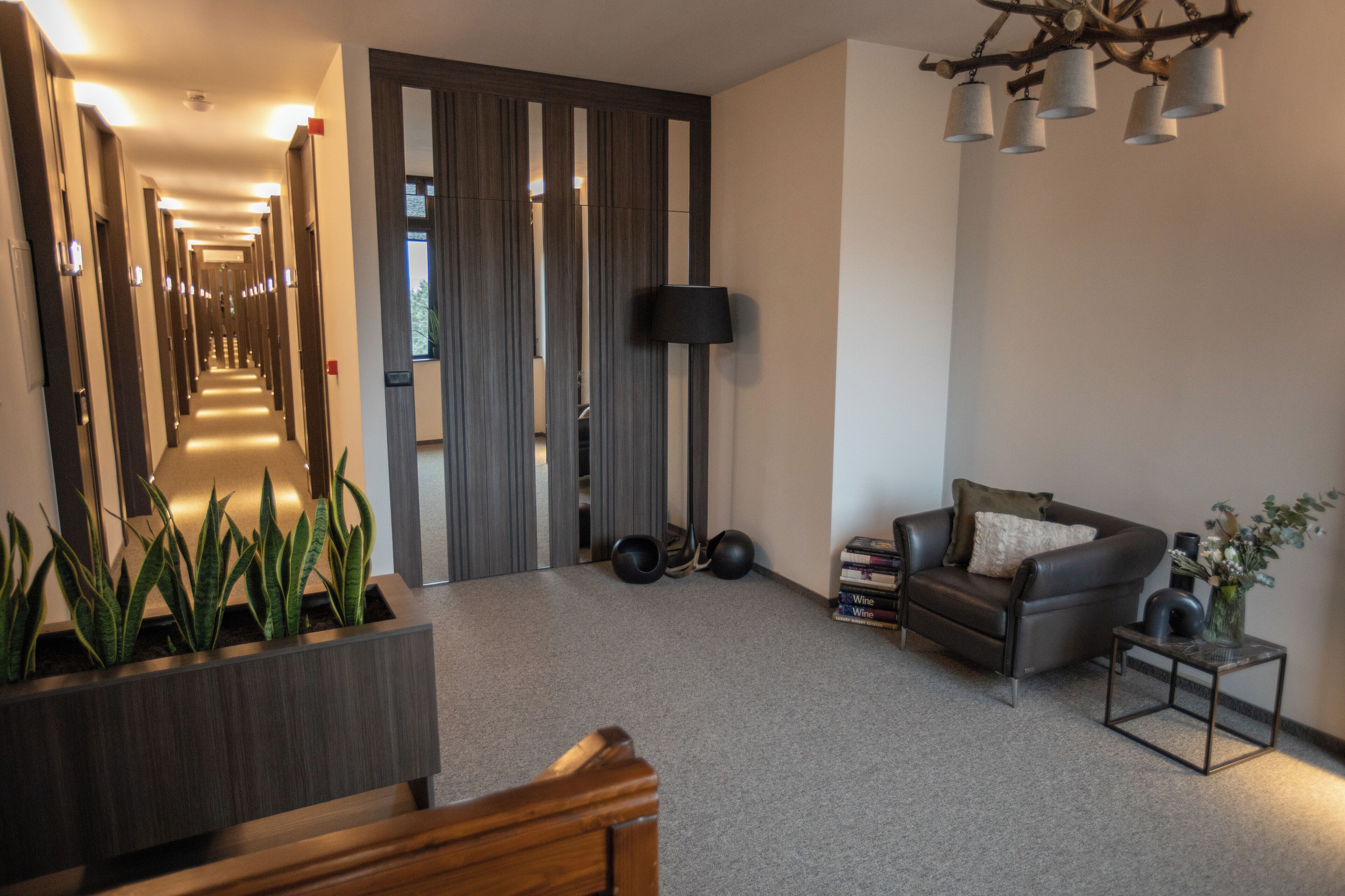 A modern hotel lobby with a long hallway, a sofa, a coffee table, and a plant.