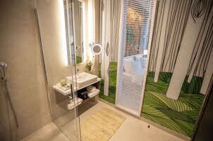 Un baño con cabina de ducha de vidrio, lavamanos con espejo y toallero.