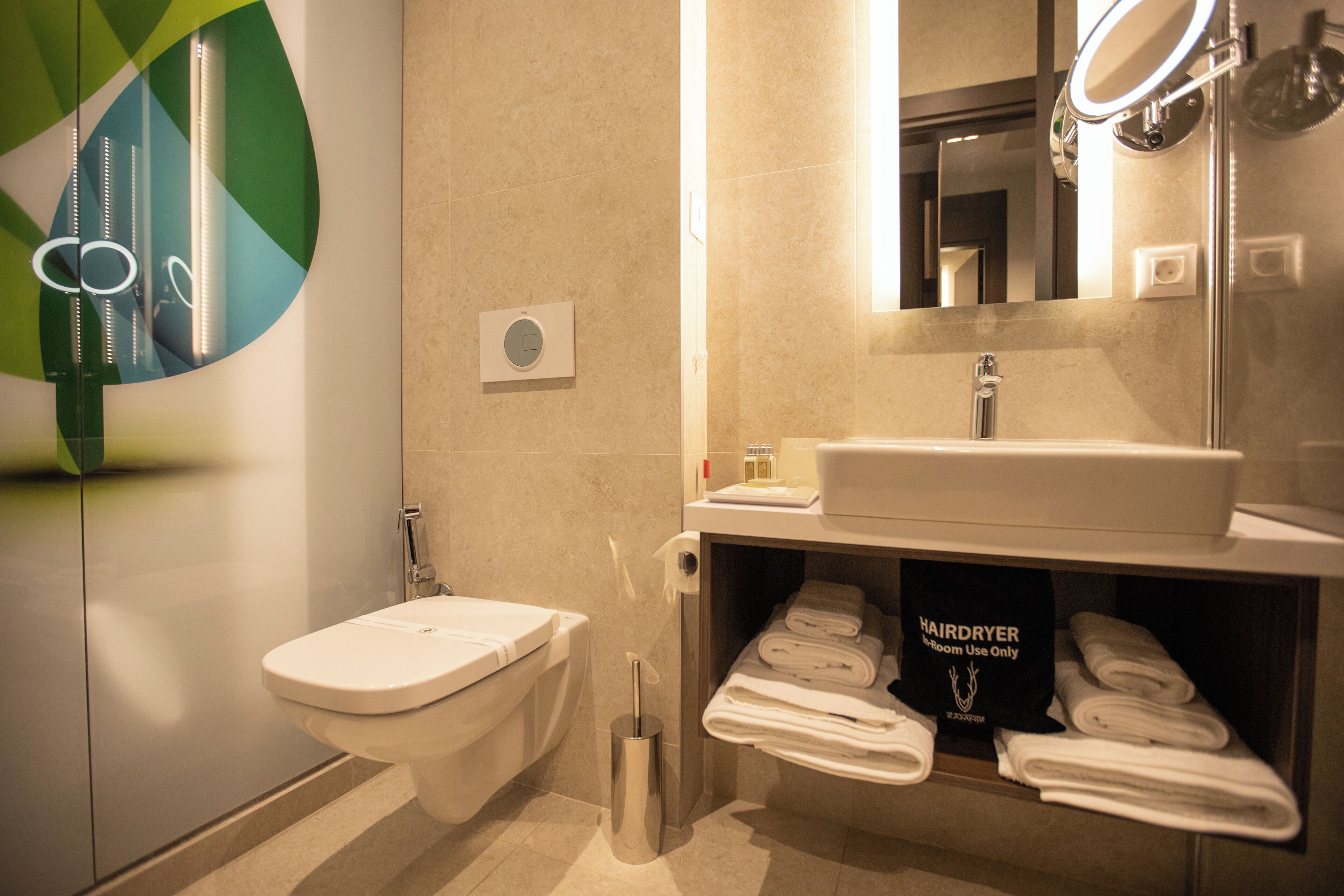 A modern bathroom with a toilet, sink, and towel rack.
