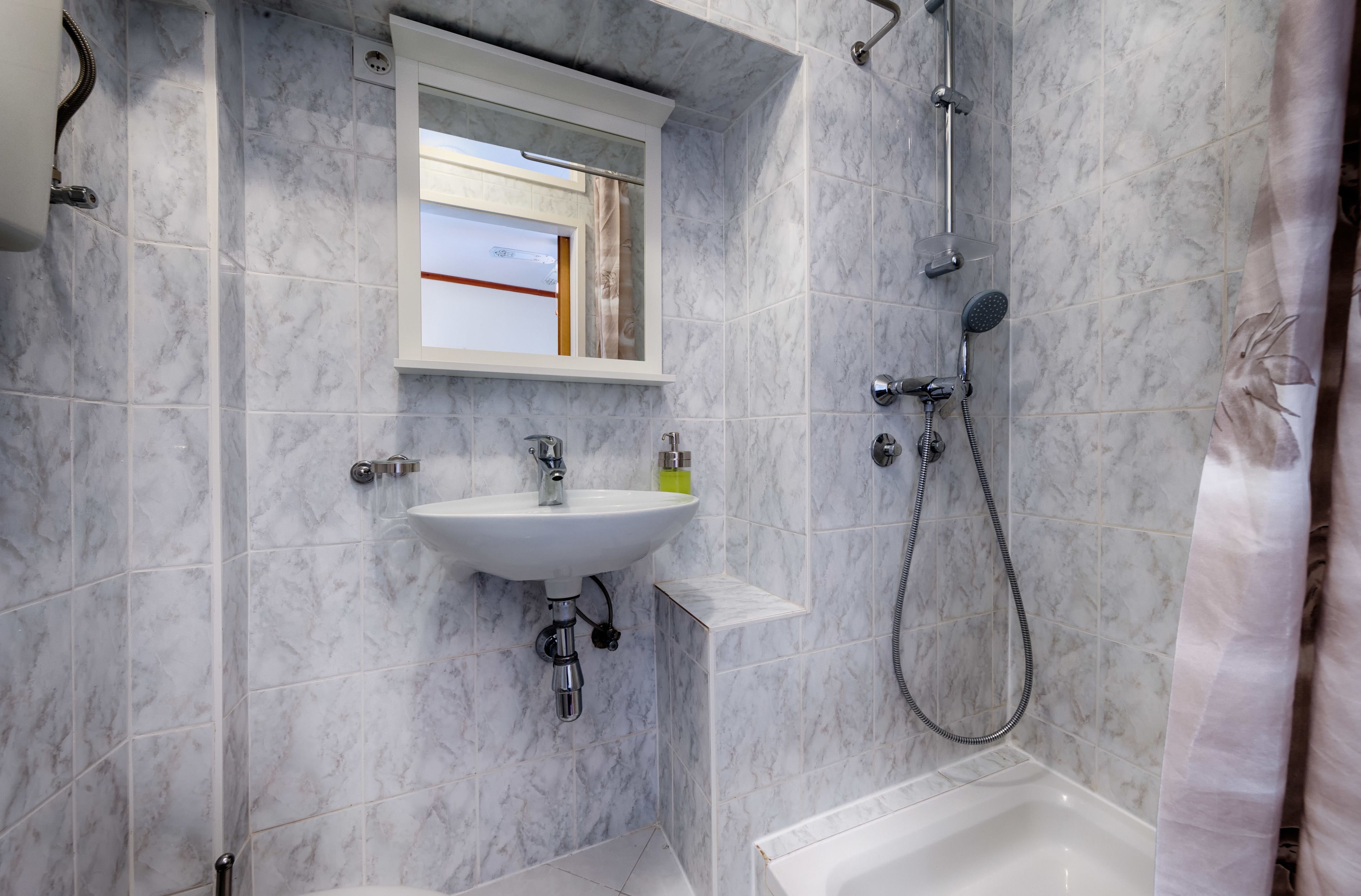 A bathroom with a white sink, a mirror, and a shower.