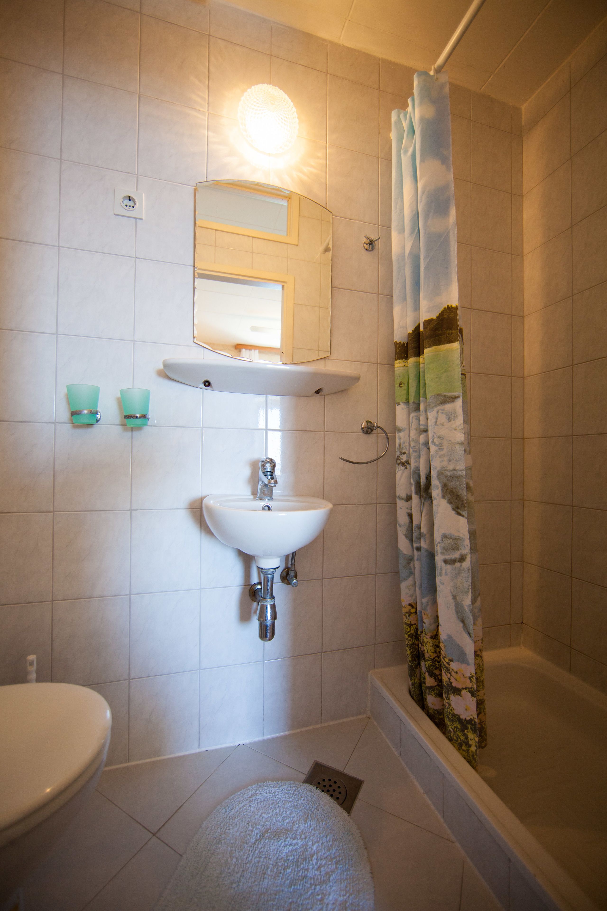 A bathroom with a sink, mirror, and shower curtain.