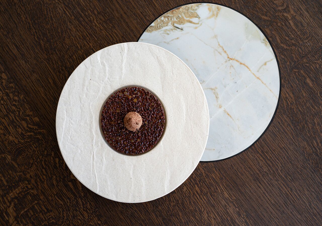 Two round, white plates with a dark substance in the center, placed on a wooden surface.