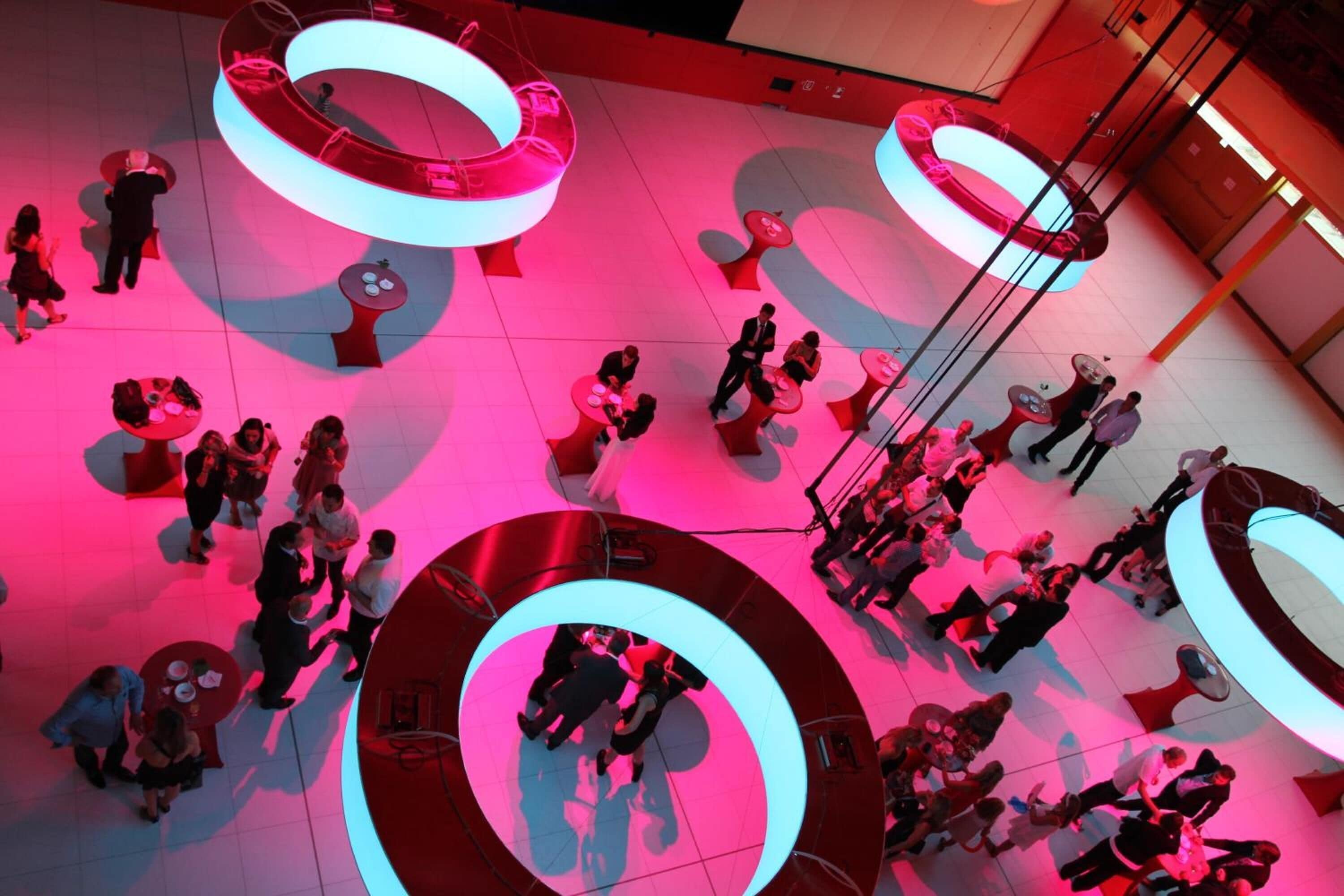 A spacious indoor area with multiple circular seating arrangements and a central stage.