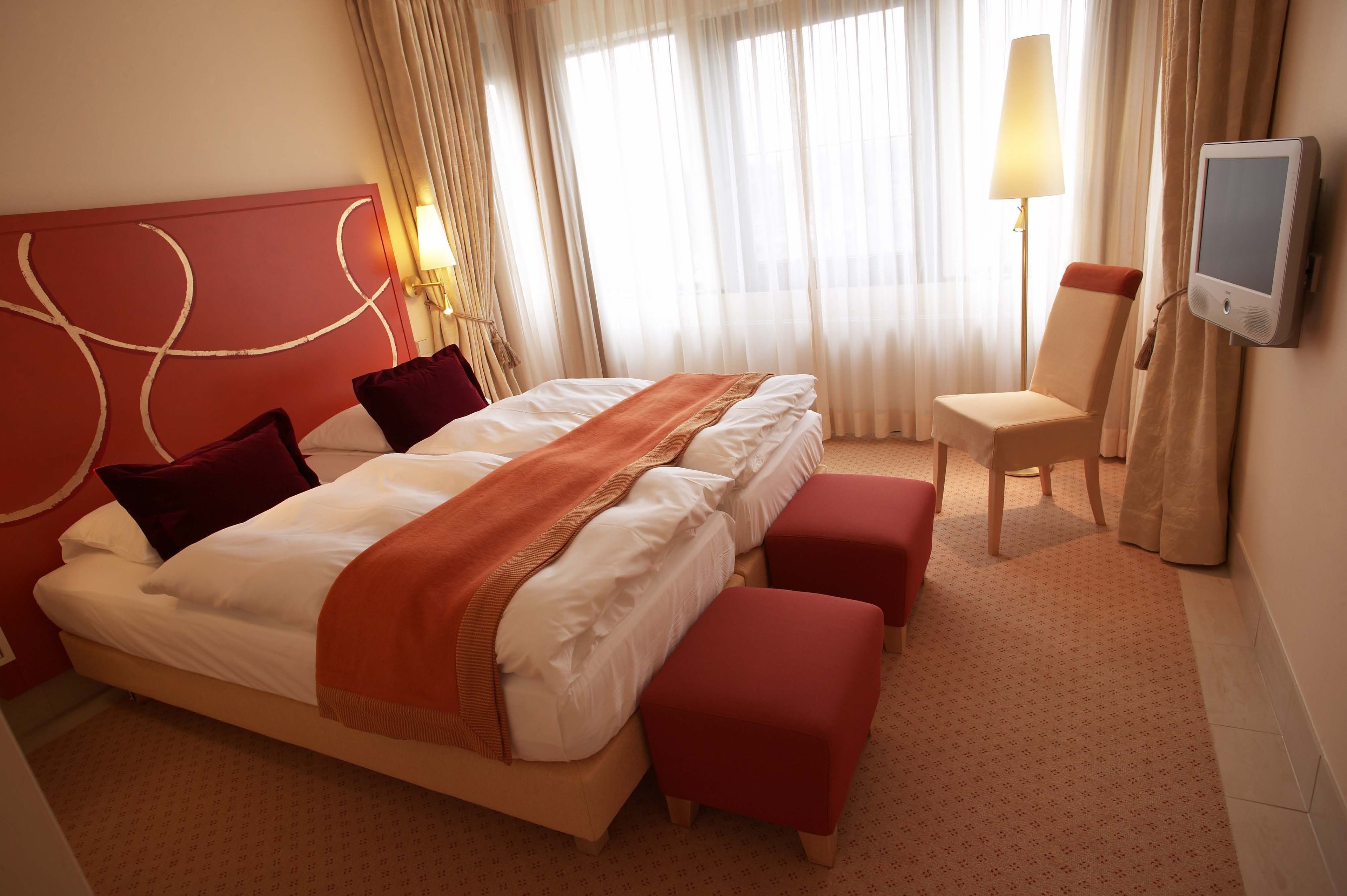 Une chambre d’hôtel avec un grand lit, une chaise, une télévision et une lampe.