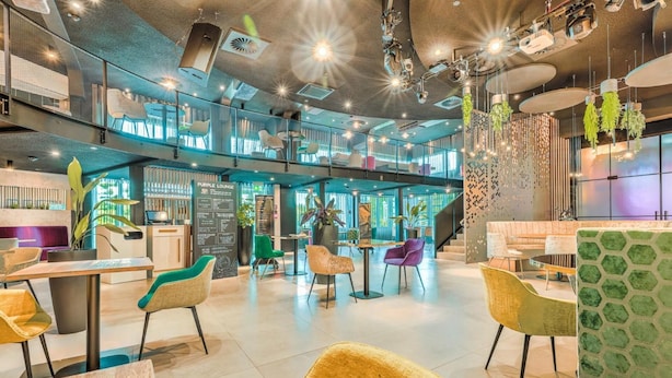 Un salón moderno con techo alto, varias zonas de estar y un menú a la vista.