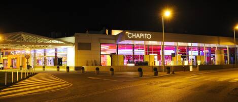 A brightly lit hotel named 'CHAPITO' with a modern facade and large windows.