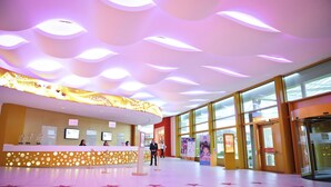 Zona de recepción de hotel con un moderno diseño de techo, un mostrador de recepción y grandes ventanales.
