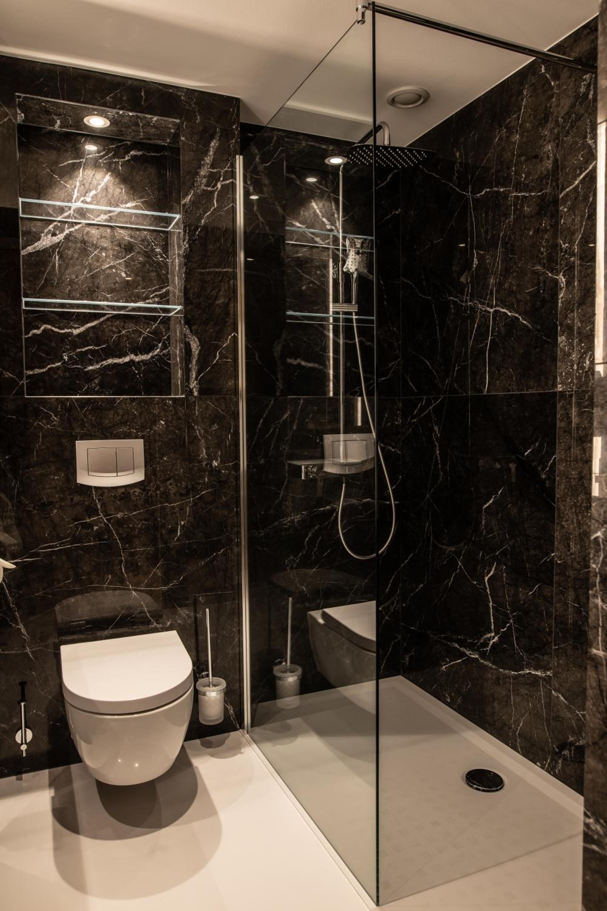 Une salle de bain moderne avec un mur en marbre, une douche à parois de verre et des toilettes.