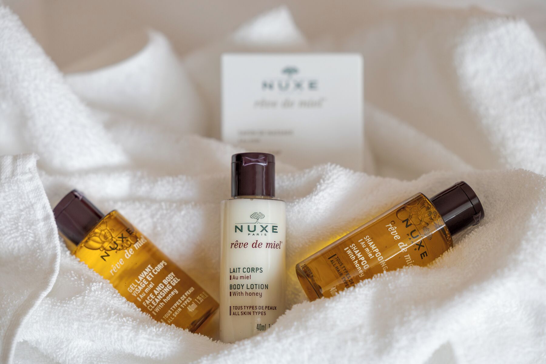 Drei Flaschen NUXE Paris Body Lotion und eine weiße Box mit dem NUXE-Logo.