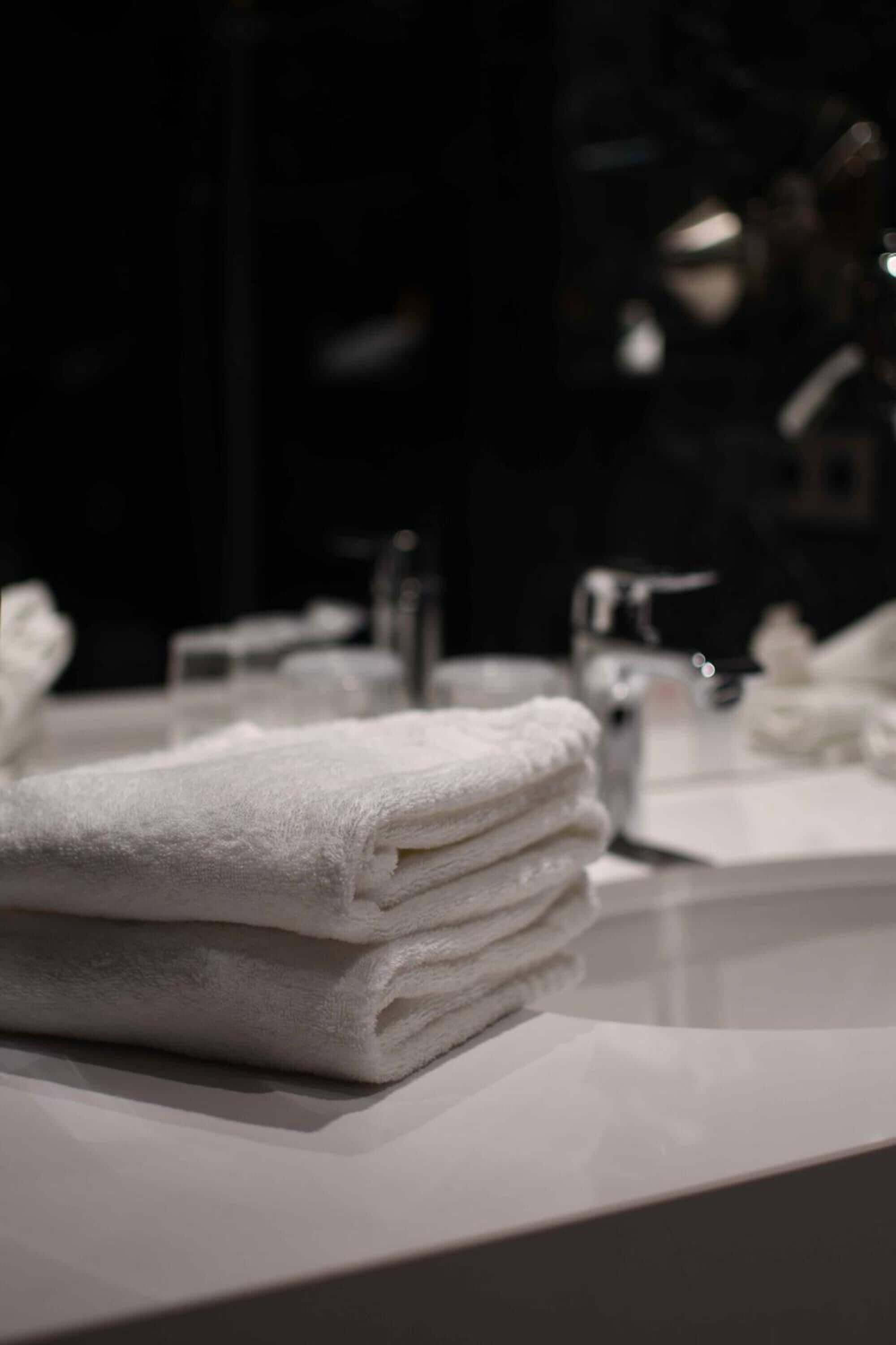 Une pile de serviettes blanches sur le comptoir d’une salle de bain.