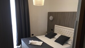 A neatly made bed with a white headboard and two black pillows, a folded white towel, and a dark-colored bedspread. - Hotel Centrale Trieste (Trieste)