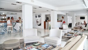 A modern, spacious living area with white furniture, a bar, and a large wall art piece. - Zhero Hotel Mallorca (Calvia)