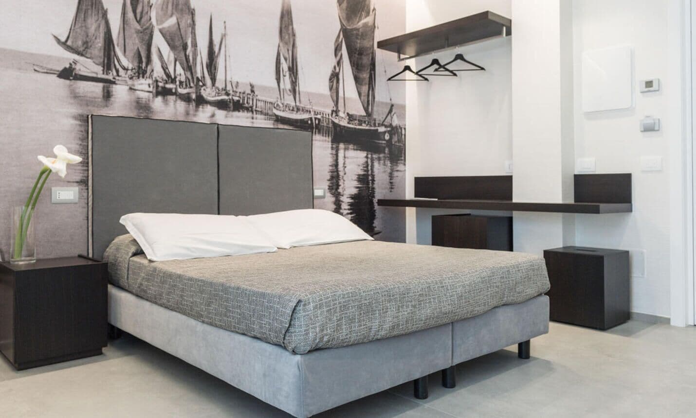 Une chambre à coucher moderne avec un grand lit, une table de chevet, une commode et un téléviseur fixé au mur.
