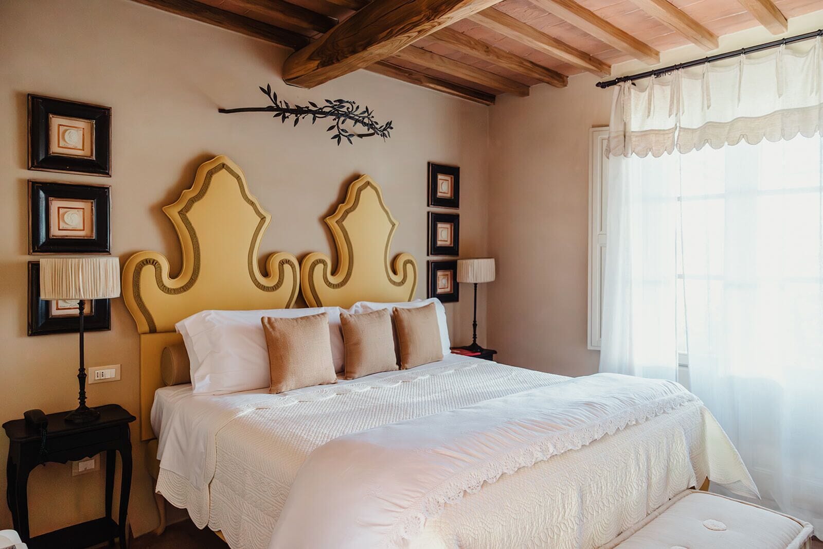 Un dormitorio con una cama grande, cuadros enmarcados en la pared y una rama decorativa.