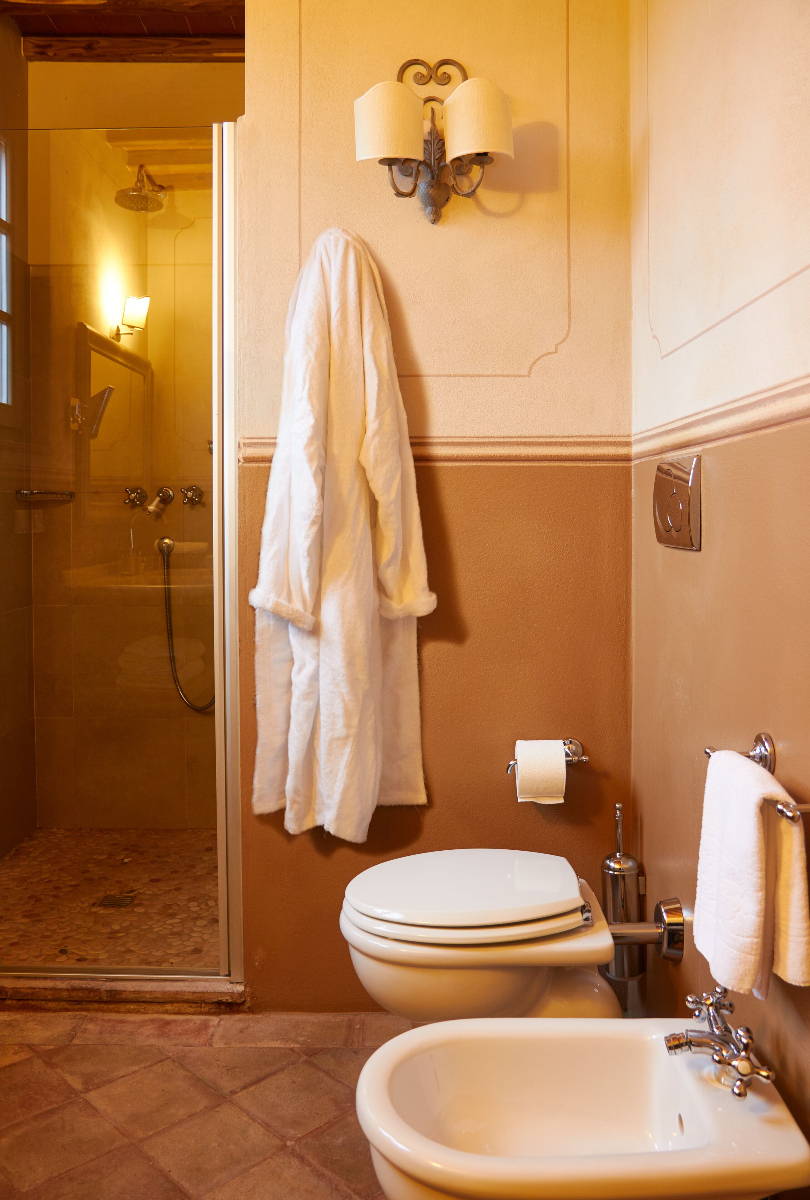 Een badkamer met een douche met glazen wand, een wastafel, toilet en een handdoekhouder.