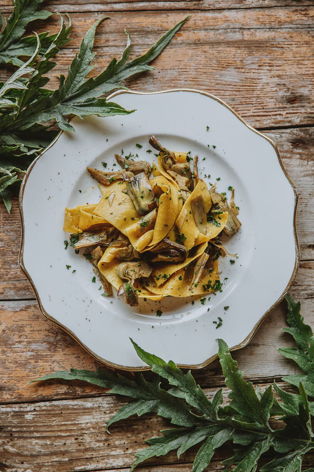 A plate of pasta with mushrooms and herbs on a rustic wooden table.