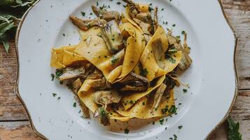 A plate of pasta with mushrooms and herbs on a rustic wooden table.