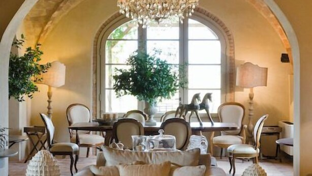 A spacious living room with a high arched ceiling, elegant chandeliers, comfortable seating, and large windows allowing natural light. - Relais Sant'Elena (Bibbona)