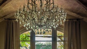 A room with a large arched doorway, a chandelier, and a view of greenery outside. - Relais Sant'Elena (Bibbona)