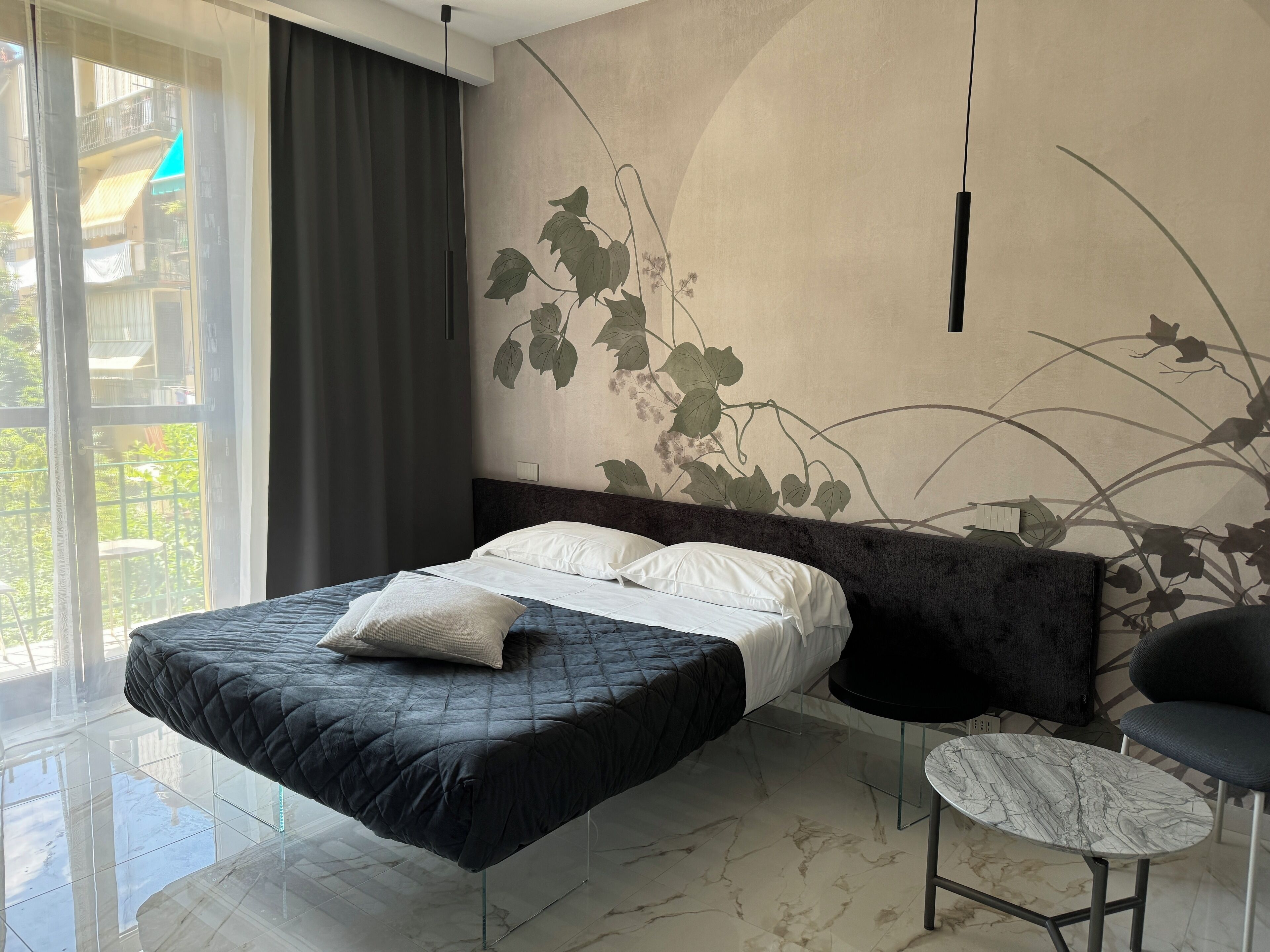 A modern bedroom with a bed, a small round table, and a view of a balcony.
