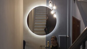 A staircase with a circular light fixture above it, a radiator, and a chair in a hallway. - Relais Stibbert Florence (Florence)